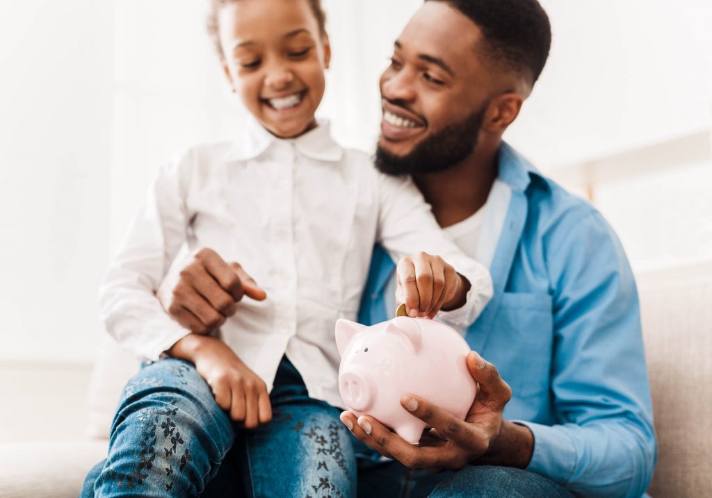 Father and child collecting coins in a pig shaped coin jar