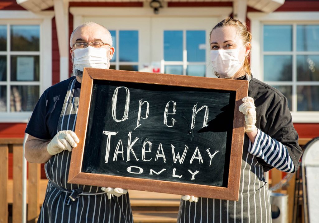Local business owners hold up a sign in front of their store