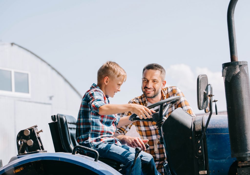 Farmer letting child sit in seat of tractor