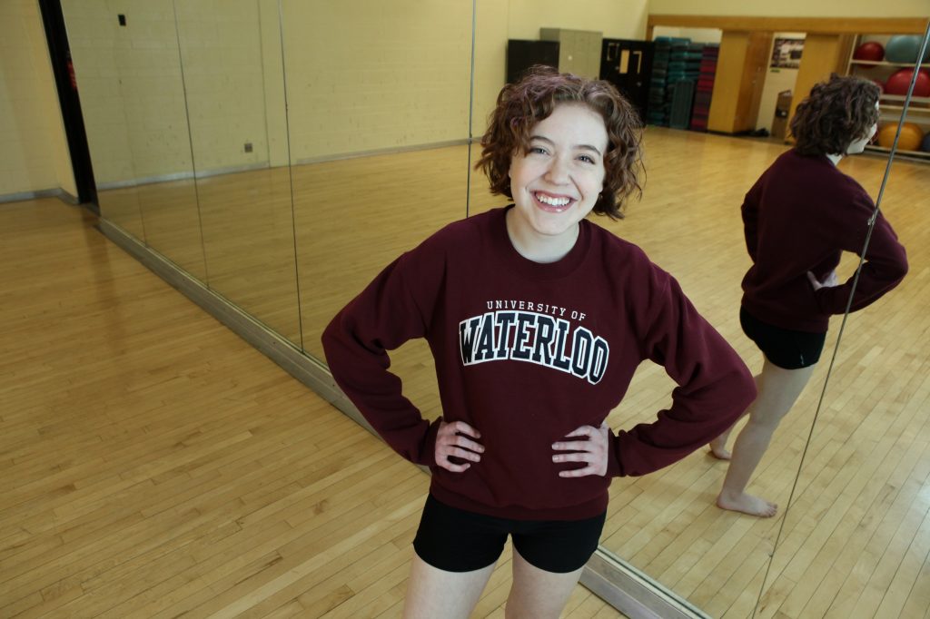 Student posing in dance classroom with a University of Waterloo sweater