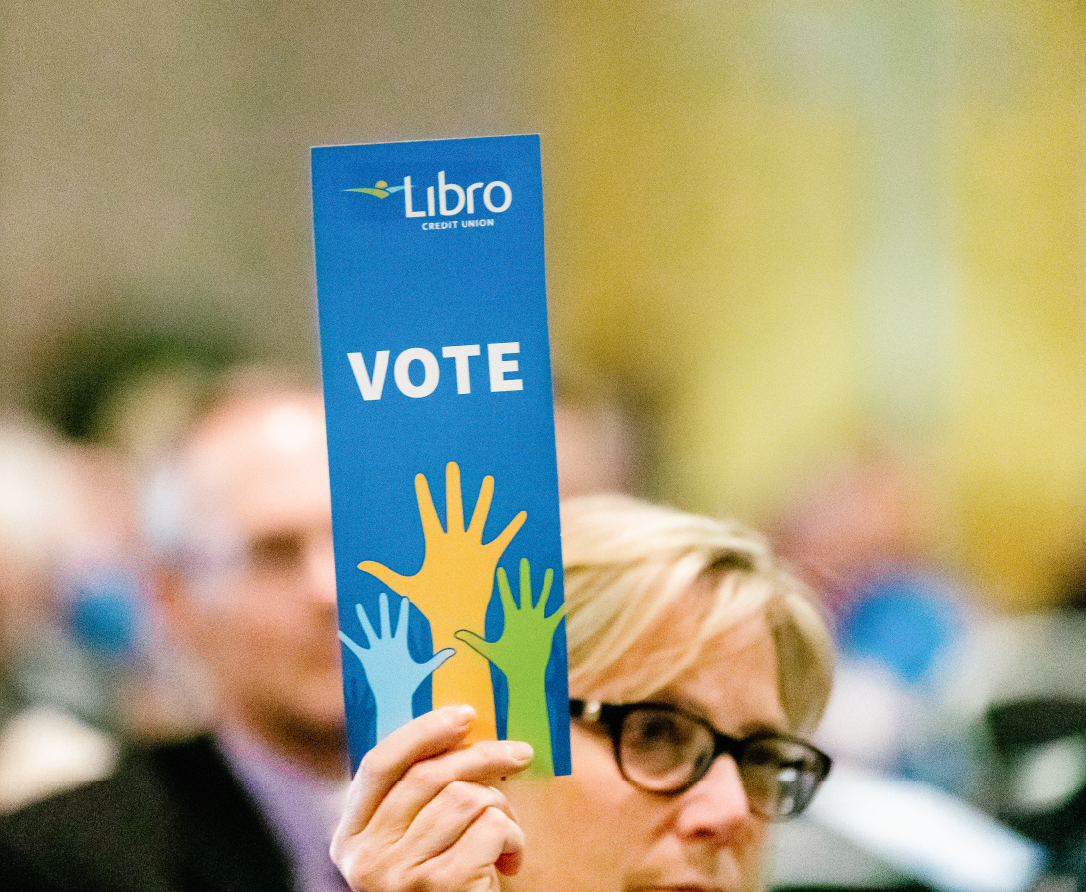 Woman holding up a voting card sign that says