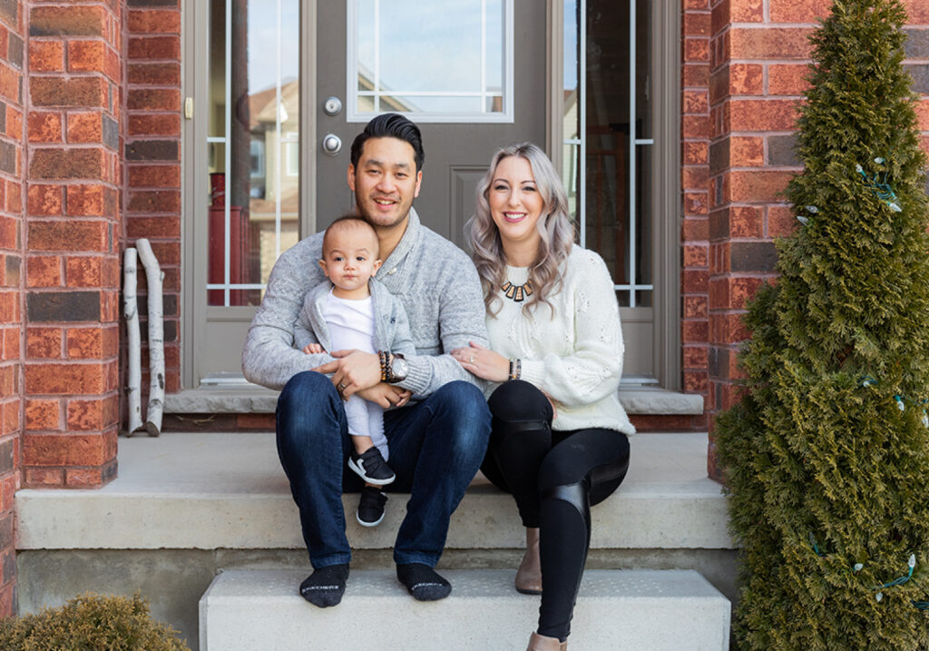 Suburban husband, wife, and baby sitting on their front porch