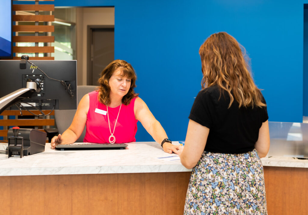 owner experience representative at a teller desk with an Owner