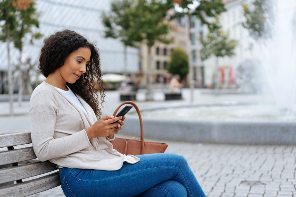 Woman sitting in park looking at her phone