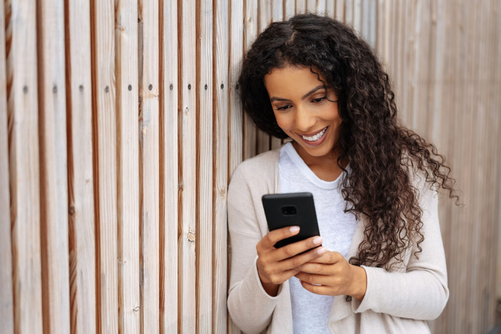 woman looking at phone leaning against wall