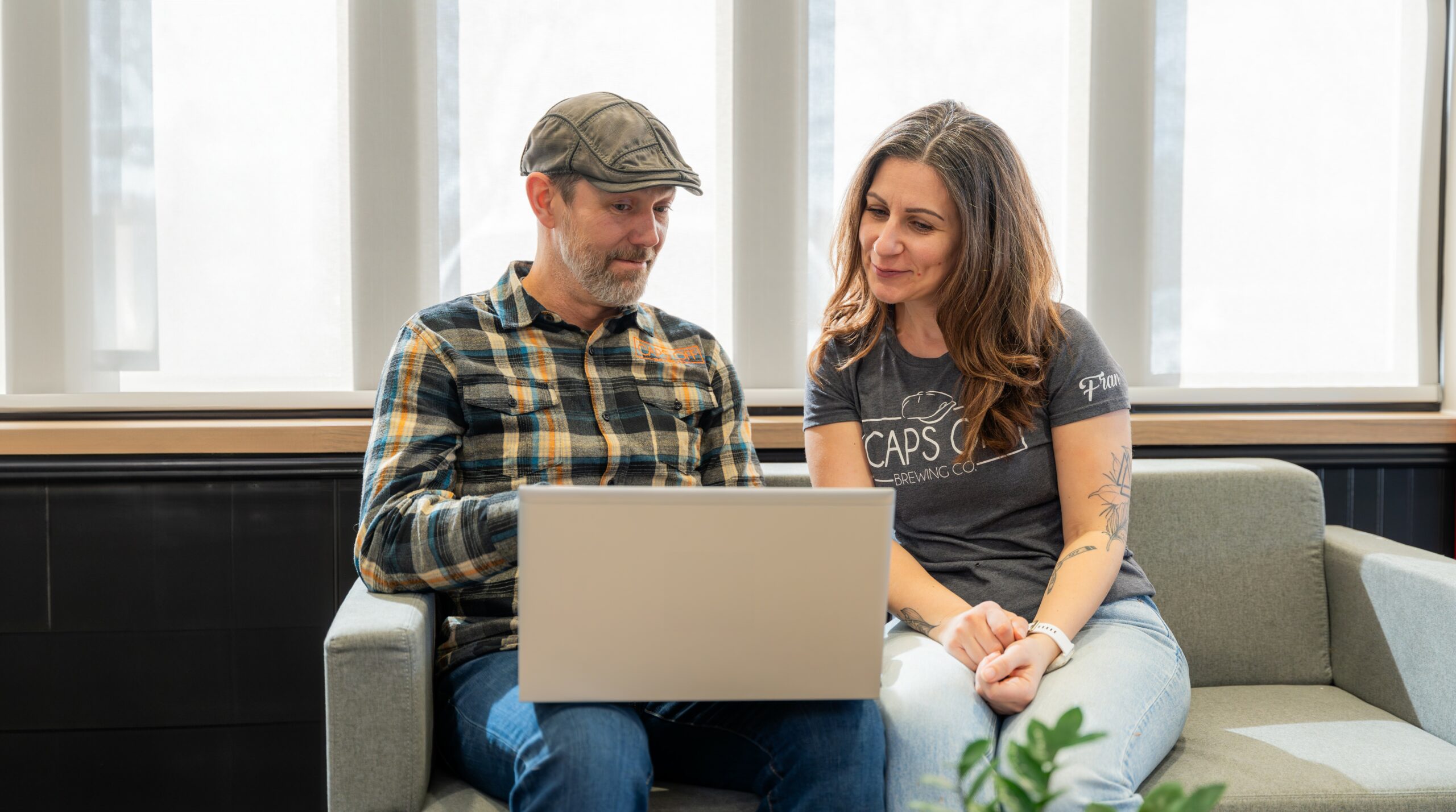 Two people sitting and looking at a laptop smiling