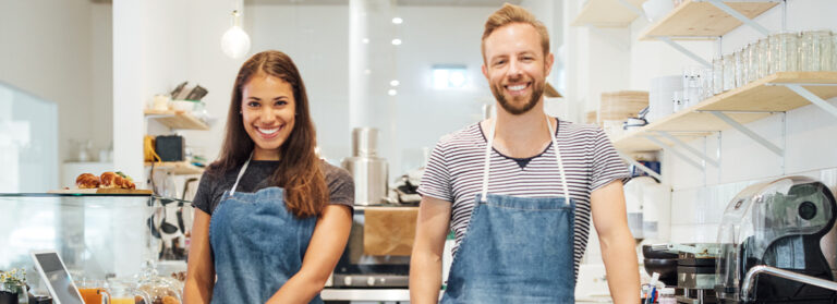 Two people smiling working at a bakery