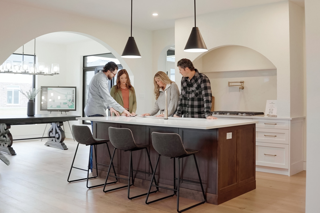 A group of people looking at designs standing around a kitchen island