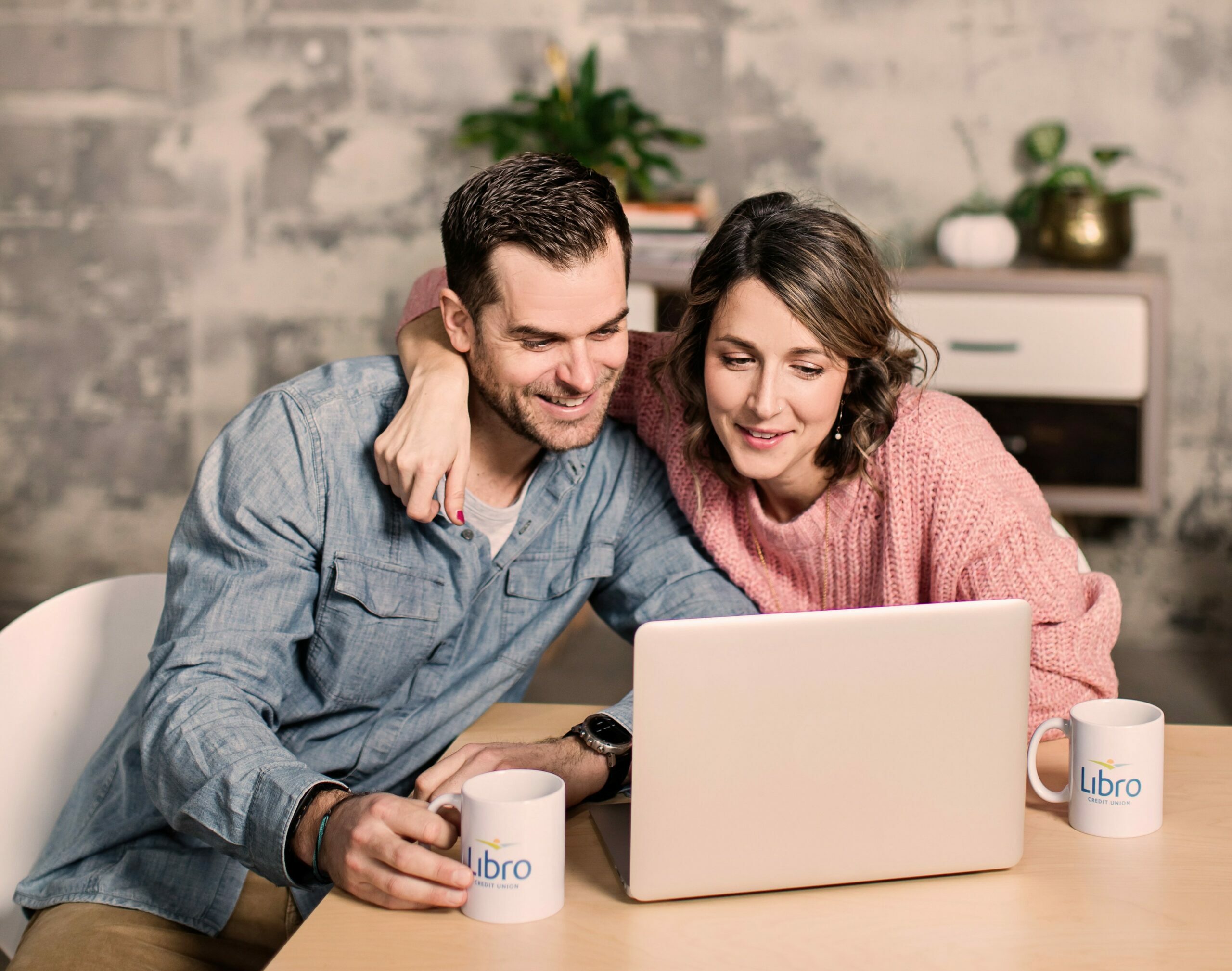Two people sitting at a table looking at a laptop