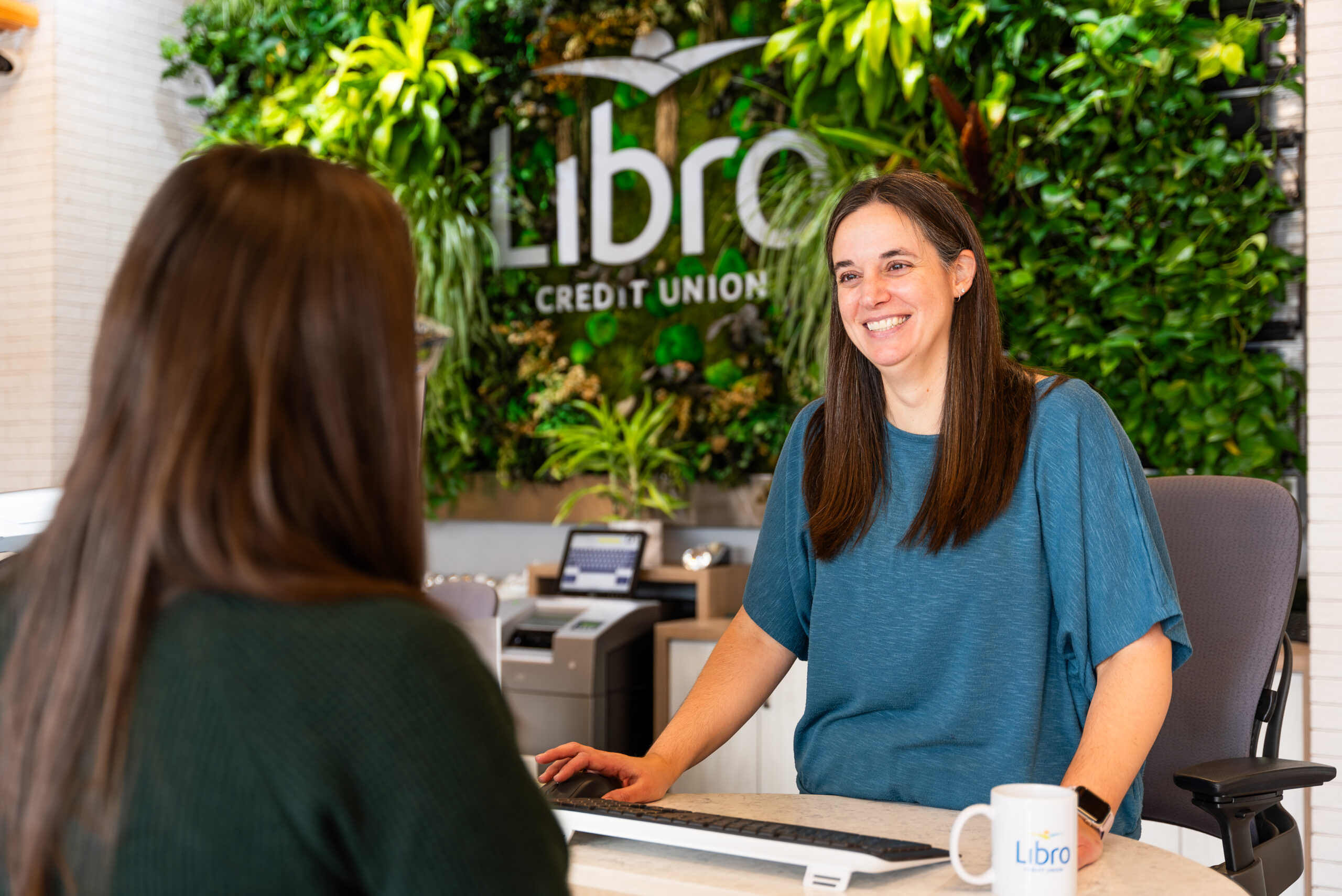 Libro Staff standing at a wicket, smiling in a libro location