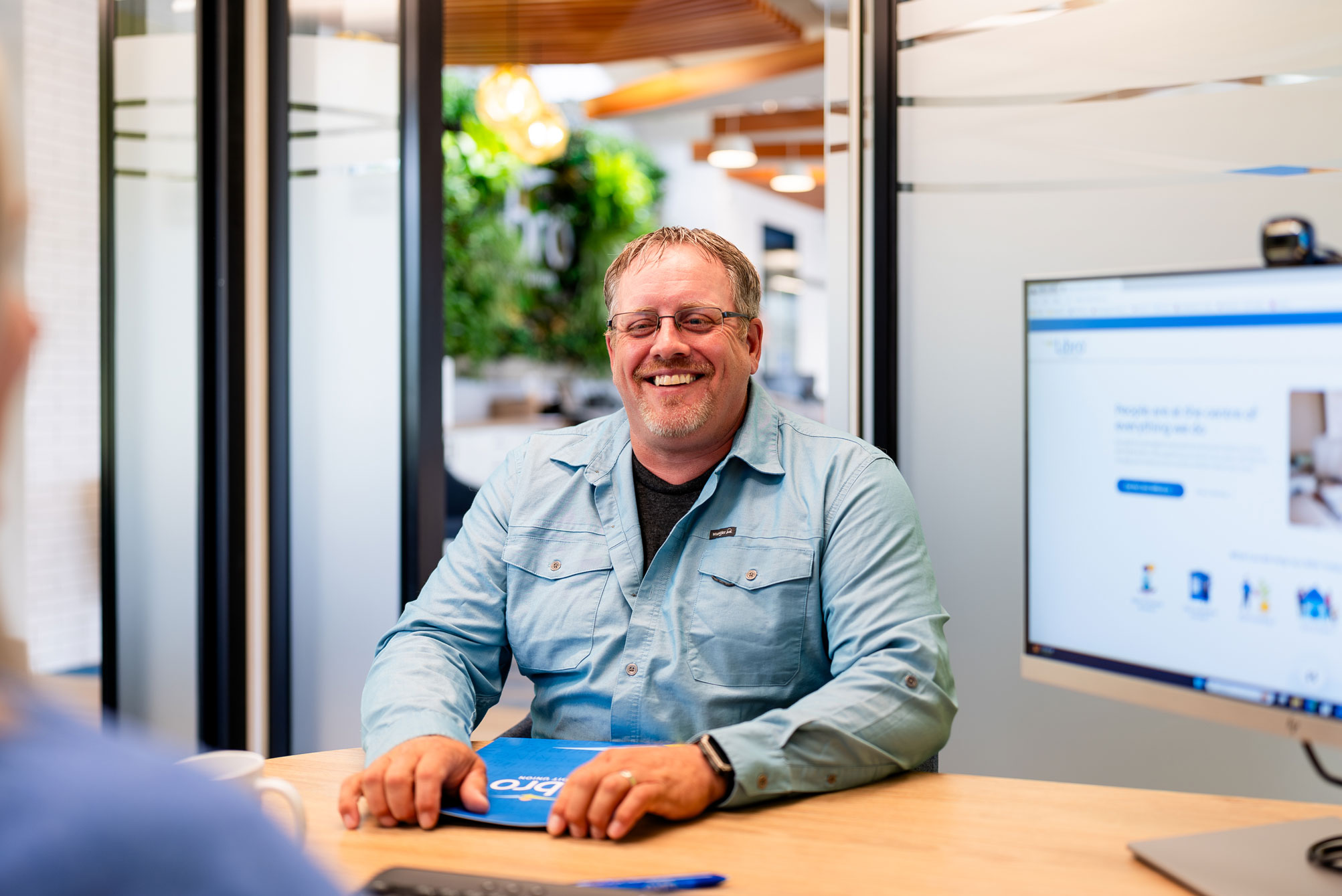 Libro Member sitting at a desk in a Libro branch, talking to a Coach