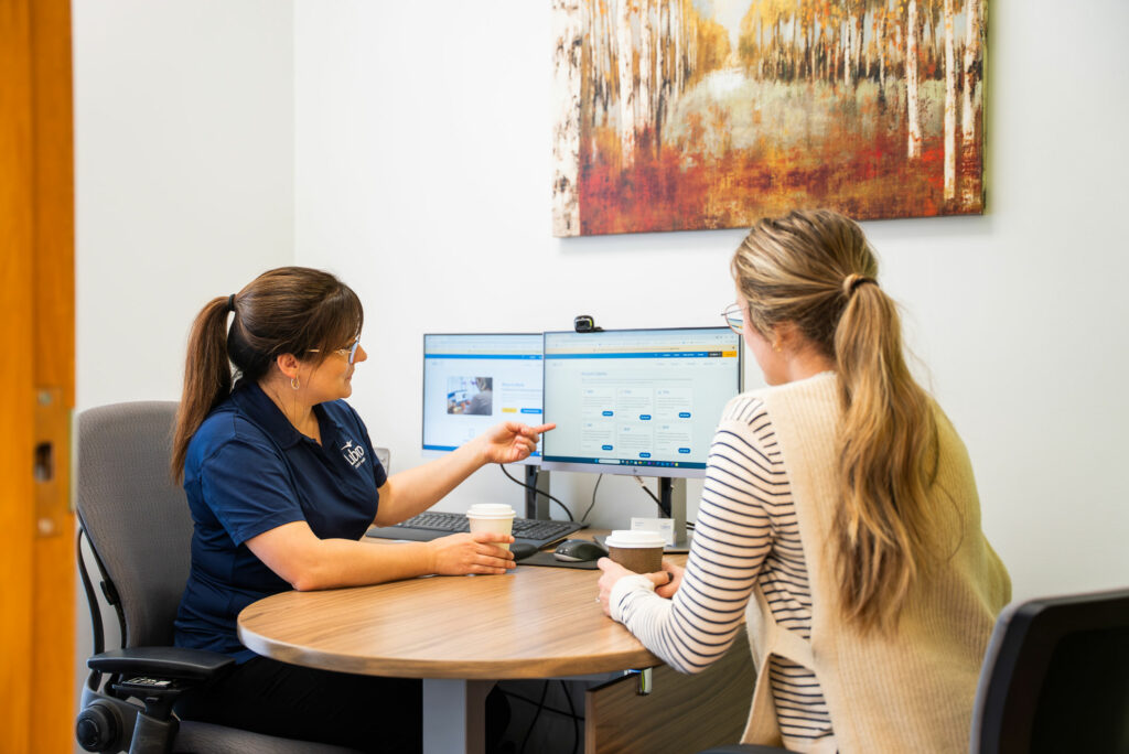 Libro Staff Amanda talking with a Libro Member and pointing at computer