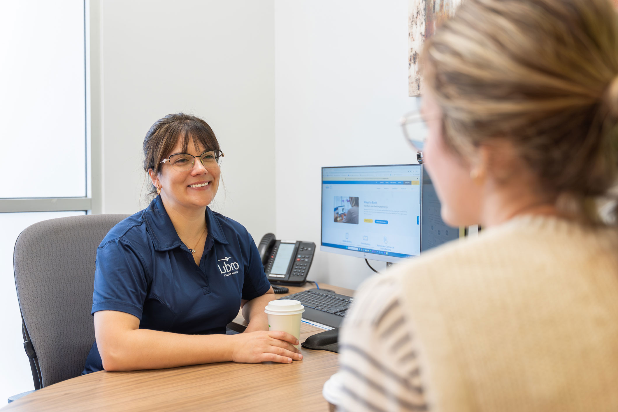 Libro Staff Amanda sitting behind a desk and smiling at a Libro Member